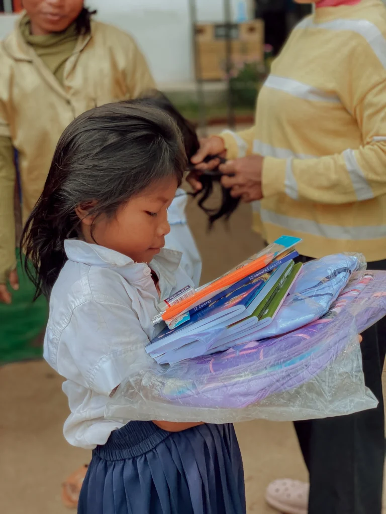 Mädchen erhält Rucksack, Schuluniform, Hefte und Stifte